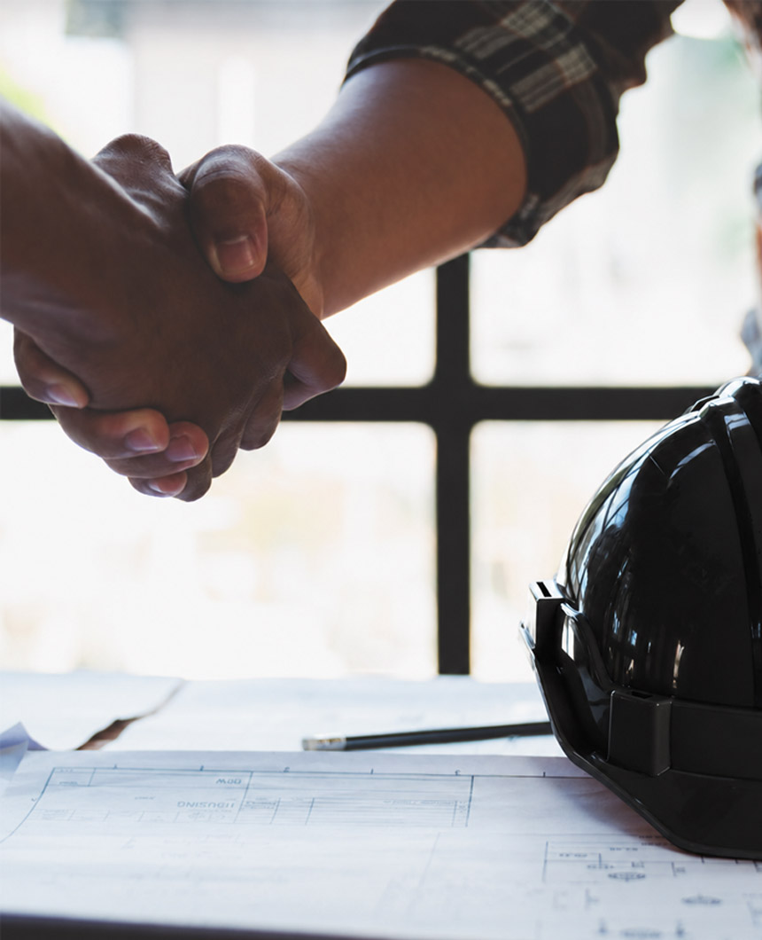 Construction professionals collaborating beside a black hardhat and technical drawings